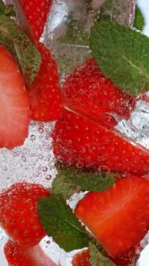 Buz küpleri ve meyvelerle bardağa maden suyu dökme hareketi. Yüksek Hız Sinema Kamerası, 1000fps