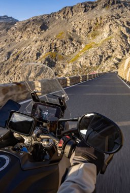 Gündoğumunda İtalyan Alpleri 'nde motosiklet süren motosiklet sürücüsü, gidon manzarası, dramatik bir gökyüzü. Seyahat ve özgürlük, açık hava aktiviteleri