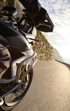 Güneş doğarken İtalyan Alpleri 'nde motosiklet süren motosikletli, çarpıcı bir gökyüzü. Seyahat ve özgürlük, açık hava aktiviteleri