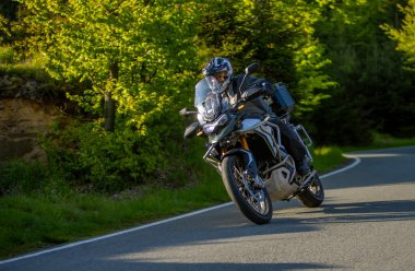 Boş asfalt yolda motosiklet süren sürücü, bulanık motivasyon, bahar dağları