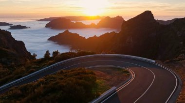 Asphalt Yolu ile Yüksek Dağ Manzarası 'nda destansı Günbatımı Manzarası. Pico do Arieiro, Madeira Adası. Vadideki bulutlar .