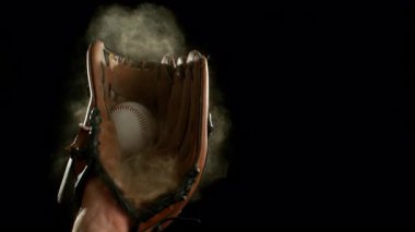 Siyah arka planda izole edilmiş kahverengi deri beyzbol eldiveni içinde süper yavaş bir el hareketi. Yüksek hızlı sinematik kamerayla çekilmiş.