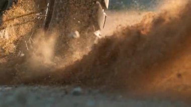 Yarışın başında motorsikletin direksiyonundan uçan kayaların ve tozun süper yavaş çekimi.