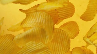 Patates cipslerinin gradyan sarı arka planda çok yavaş hareket etmesi. Yüksek hızlı sinema kamerası, 1000 fps..