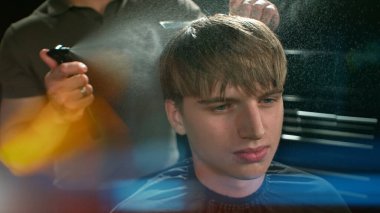 Berber dükkanındaki sakallı genç adam. Berber saç kesimini hazırlıyor. Karanlık Atmosfer, Kara Arkaplan. Berber ve Müşteri kavramı.