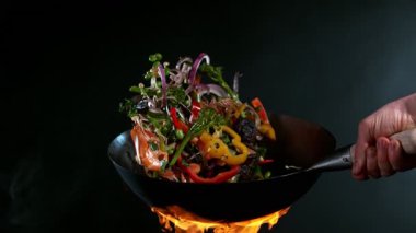 Uçan Asya tavası malzemelerinin süper yavaş çekimi. Yüksek hızlı sinema kamerası, 1000 fps.