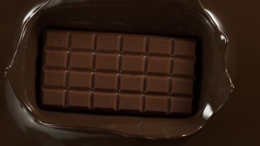 Çikolata masası sıcak çikolatanın içine düşer. 1000 fps hızla yüksek hızlı sinematik bir kamera ile çekildi.