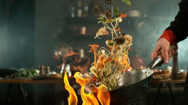 Tavada taze malzemelerle çırpılmış alevler uçuyor.