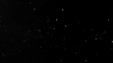 Siyah zemin üzerinde izole edilmiş küçük parçacıklar uçuşuyor. Yüksek hızlı kamera, 1000 fps.