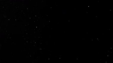 Siyah zemin üzerinde izole edilmiş küçük parçacıklar uçuşuyor. Yüksek hızlı kamera, 1000 fps.