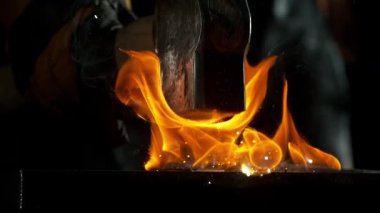 Demirciye yakın plan örsün üzerinde kızgın demirden uçan kıvılcımlar dövüyor. Süper yavaş çekim, 1000 fps hızla yüksek hızlı sinema kamerasıyla çekildi.