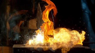 Demirciye yakın plan örsün üzerinde kızgın demirden uçan kıvılcımlar dövüyor. Süper yavaş çekim, 1000 fps hızla yüksek hızlı sinema kamerasıyla çekildi.