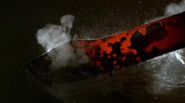 Demirci kızgın, dövülmüş metal parçayı suya koyar. Süper yavaş çekim, 1000 fps hızla yüksek hızlı sinematik kamerayla çekildi.