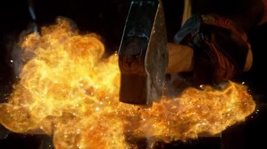 Demirciye yakın plan örsün üzerinde kızgın demirden uçan kıvılcımlar dövüyor. Süper yavaş çekim, 1000 fps hızla yüksek hızlı sinema kamerasıyla çekildi.