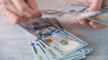 Kadın elleri 100 Amerikan doları banknotlarını sayıyor. Yüz dolarlık banknotları sayıyorum. Amerikan parası. Kapat.