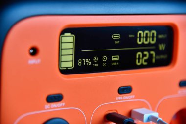 Orange portable charging station with status display screen. Concept of backup energy and technology. Close up clipart