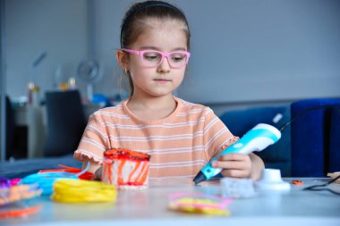Sanattaki yaratıcılığa ve yeniliğe odaklanmış renkli bir yapı yaratmak için 3D kalem kullanan bir kız..