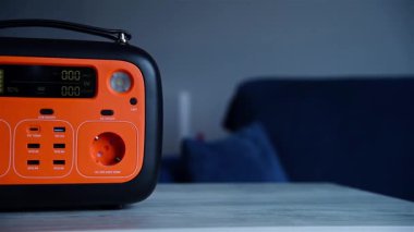Taşınabilir elektrik santrali, parlak turuncu panel, taşınabilir şarj istasyonundaki kapalı bir masada. Teknoloji ve yedek enerji kavramı. Yavaş Hareket Efekti.