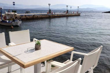 Beyaz sandalyeli ve deniz kenarındaki masalı romantik Yunan restoranı ve turizm seyahati .