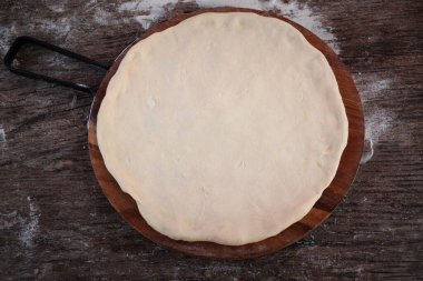 Pizza için taze çiğ hamur ya da ahşap kesim tahtasının üzerinde ekmek pişirmek için koyu kırsal arka planda. Üst görünüm .