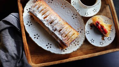 Traditional freshly baked whole apple strudel on wooden table, close up. Fresh homemade pastries with fruit or berry filling .