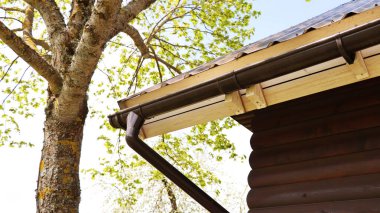 Yağmur oluğu boru hattı sistemi kurulumu. Çatı İnşaatı. Yağmur oluğu sistemi ve çatısı kardan korunuyor 