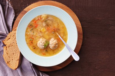 Siyah arka planda köfteli çorba, gri keten peçete. Sebzeli köfte çorbası. Üst görünüm