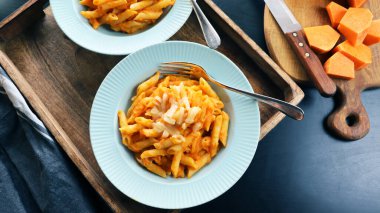Kabak soslu makarna ve koyu arkaplanda parmesan peyniri. Kremalı vejetaryen vejetaryen kabaklı makarna.