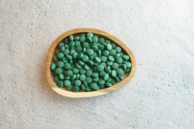 yeşil hap chlorella veya spirulina yosununa ahşap kase. Yeşil arpa chlorella.