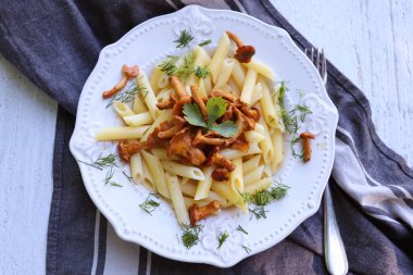 Tereyağlı mantarla kızartılmış makarna sarımsaklı mantar ve kırsal bir arka planda kareli peçetede ince doğranmış otlar.