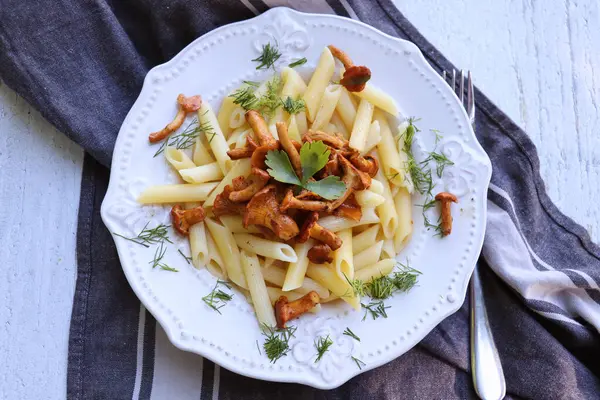 Tereyağlı mantarla kızartılmış makarna sarımsaklı mantar ve kırsal bir arka planda kareli peçetede ince doğranmış otlar.