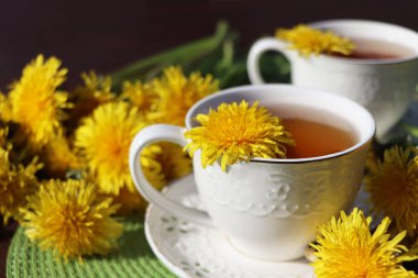 Fincanın içinde taze sarı bir çiçek olan karahindiba çayı. Vitamin içeceği. Sağlık için karahindiba bitkisi çayı.