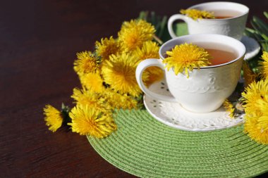 Fincanın içinde taze sarı bir çiçek olan karahindiba çayı. Vitamin içeceği. Sağlık için karahindiba bitkisi çayı.