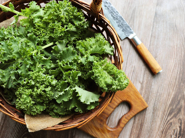 Fresh green curly kale leaves on a wooden table. Selective focus. Rustic style. Healthy vegetarian food