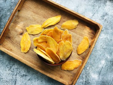 Ahşap kasede kurutulmuş mango şeritleri. Dilimlenmiş, susuz mango. Sarı renkli sulu tropikal meyve.