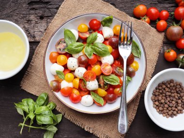 Olgun domatesli İtalyan caprese salatası, taze fesleğen ve ahşap zemin üzerinde mozzarella peyniri..