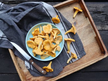 Bir kase chanterelle mantarı ahşap arka planda Cantharellus cibarius, yaygın olarak Chanterelle, altın chanterelle ya da Girolle olarak bilinir.