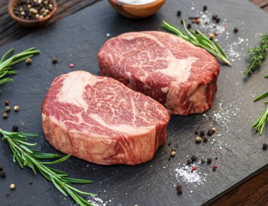 Gri tahtada tuzlu ve otlu çiğ pirzola bifteği. Üst görünüm.