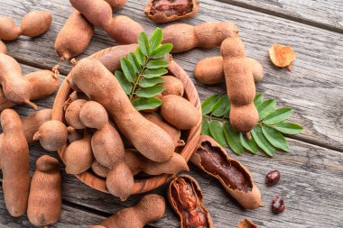 Olgun demirhindi meyvesi, yapraklar ve ahşap masada biraz demirhindi tohumu..