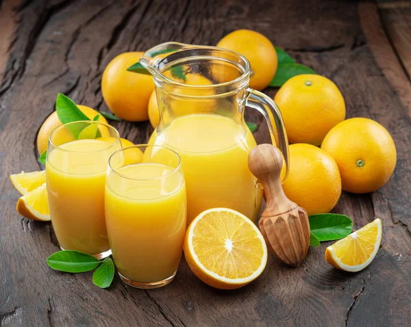 Yellow orange fruits and fresh orange juice isolated on dark wooden background.