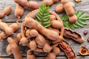 Olgun demirhindi meyvesi, yapraklar ve ahşap masada biraz demirhindi tohumu..