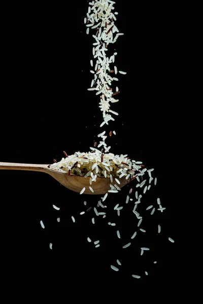白色的米粒落在勺子的黑色背景 受欢迎的食物和意大利面及意大利面的主要配料 — 图库照片