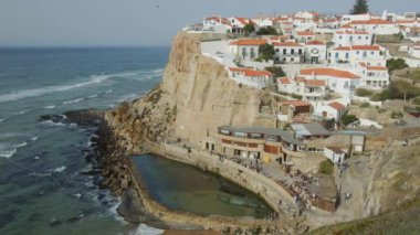 Okyanus kıyıları gün batımında Azenhas 'ta Mar, Portekiz, Sintra yakınlarındaki Colares bölgesinde. Azenhas do Mar Portekiz 'de popüler bir turizm merkezidir. Kırmızı çatıları olan güzel beyaz evler görünür..