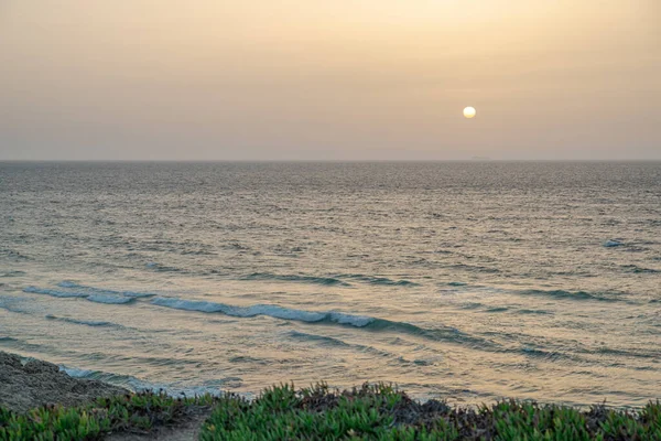 穏やかな大西洋の砂浜で美しい夕日 砂浜に接近する長い泡立ち波 — ストック写真