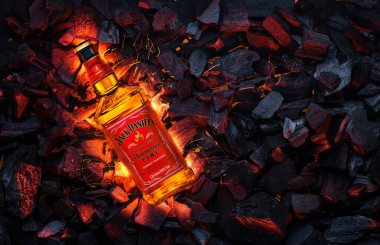 Ukrayna, Kiev. 12 Kasım 2020. Bir şişe Jack Daniels Whiskey Tennessee Fire yanan kömürlerin üstünde.
