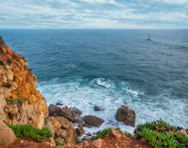 Güzel bulutlu gökyüzü ve köpüklü dalgalar Atlantik Okyanusu 'nun kayalık kıyılarına yaklaşıyor. Portekiz 'in güzel doğa geçmişi.