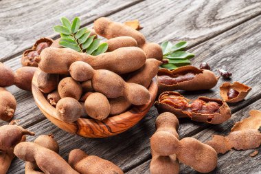 Olgun demirhindi meyvesi, yapraklar ve ahşap masada biraz demirhindi tohumu..