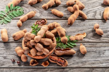 Olgun demirhindi meyvesi, yapraklar ve ahşap masada biraz demirhindi tohumu..