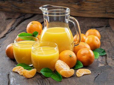 Portakal rengi mandalina meyveleri ve koyu ahşap arka planda taze mandalina suyu..