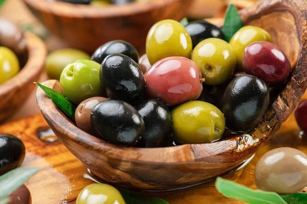 Kalamata, ahşap kasede yeşil ve siyah zeytin. Gıda arkaplanı.